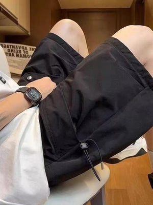 Black lightweight cargo shorts with drawstring detail and pockets, worn by a man.