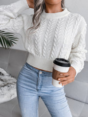 White cable knit cropped mock neck sweater with textured sleeves and ribbed hem.