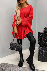Relaxed knit sweater in Deep Red with cape sleeves and a boatneck, styled with black pants and boots.