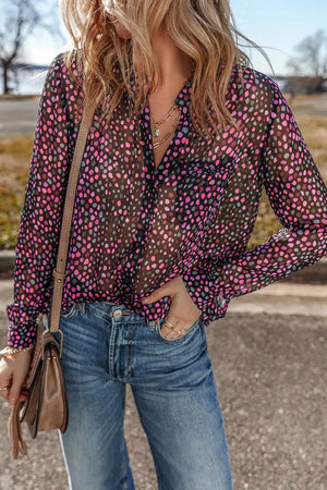 Sheer dotted blouse in black with knot detail and button cuffs, styled with jeans.