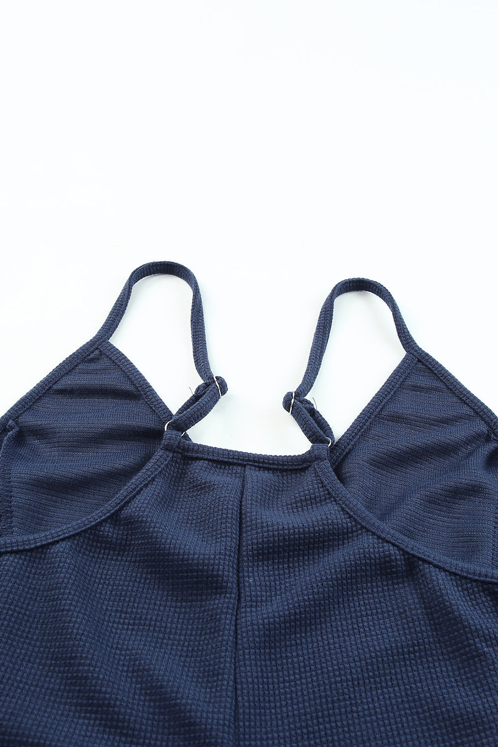 Navy jersey jumpsuit with adjustable spaghetti straps and a V-neckline.