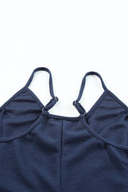 Navy jersey jumpsuit with adjustable spaghetti straps and a V-neckline.