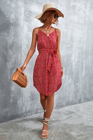 Red daisy print slip dress with tie waist, V-neck, and spaghetti straps.