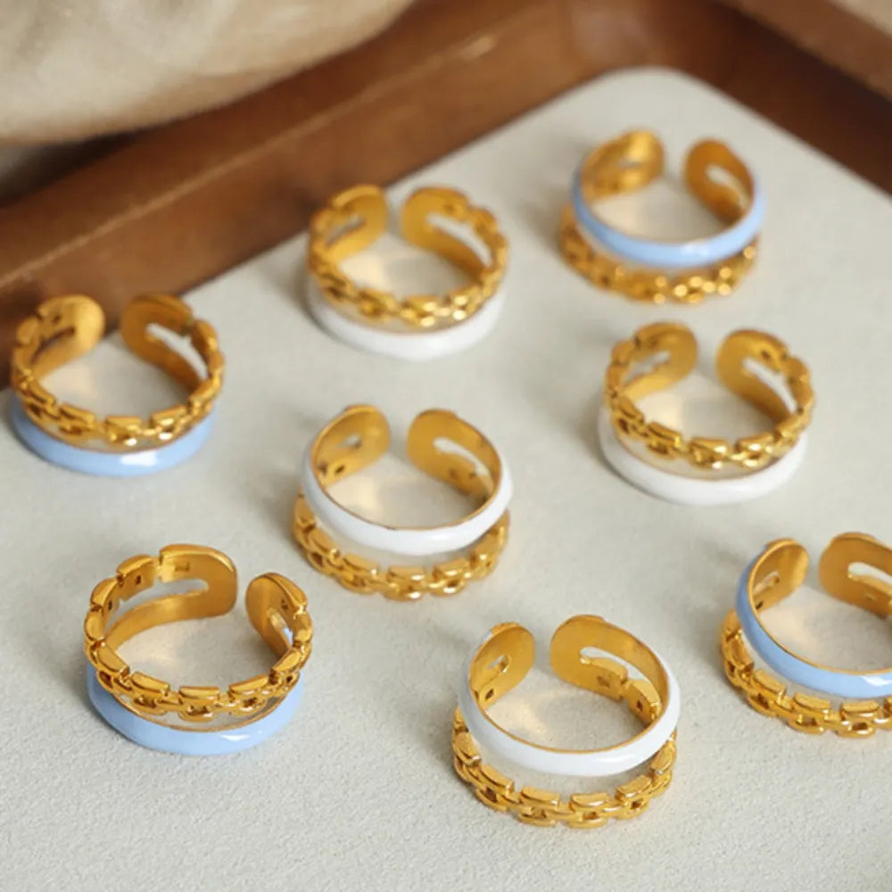 Gold chain link open ring with light blue or white enamel band detail.