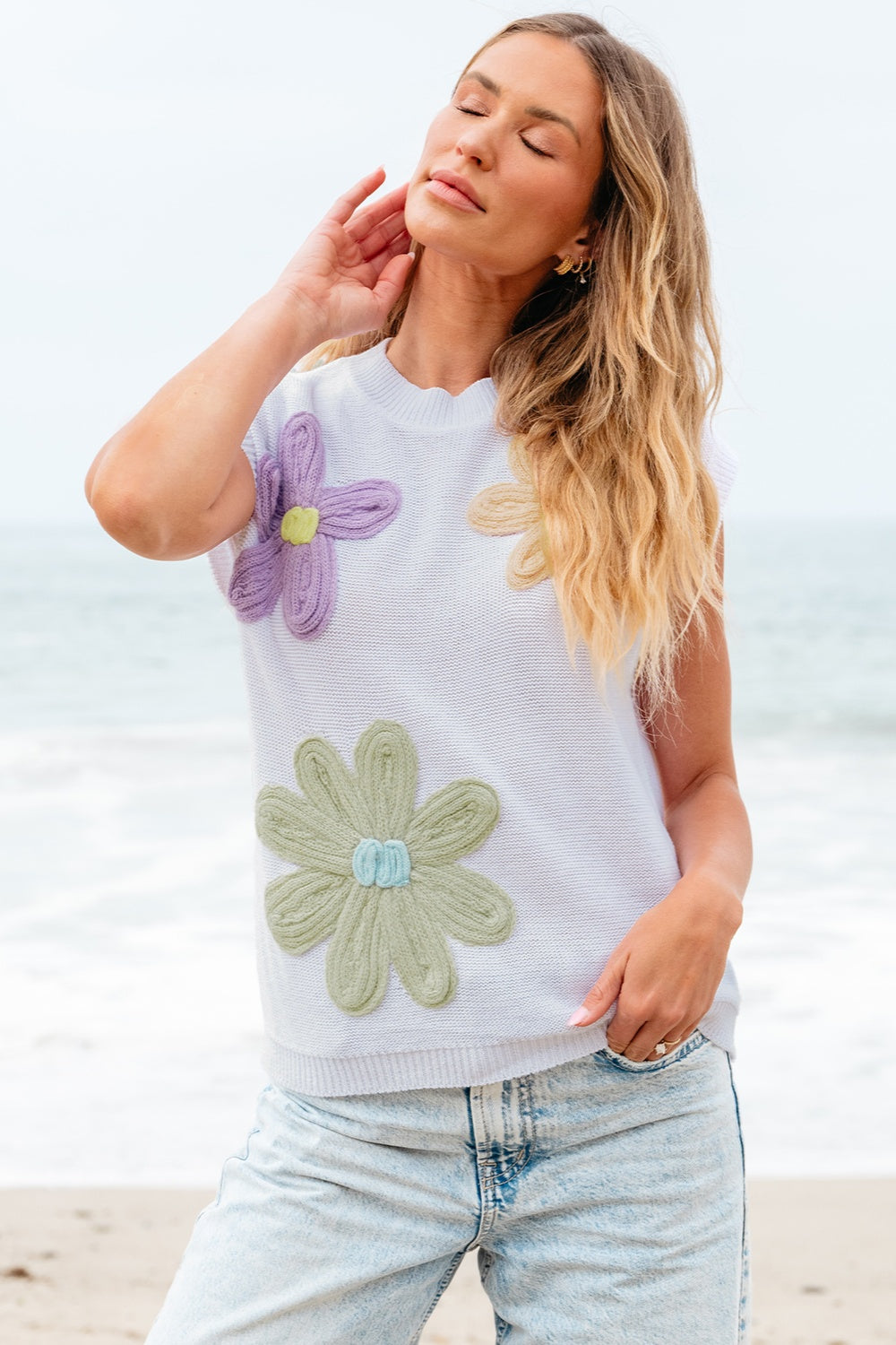 White knit sleeveless top with embroidered floral appliques in purple, green, and tan.