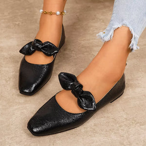 Black square toe slip-on flats with bow detail and ankle strap.