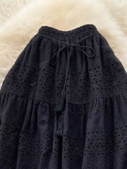 Black eyelet tiered maxi skirt with drawstring waist and tassel detail.