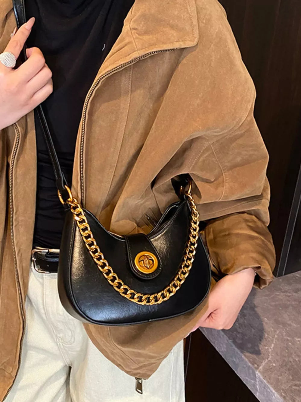 Black crescent mini shoulder bag with gold chain accent and turn-lock closure.