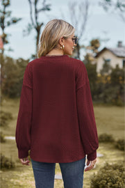 Burgundy textured cable knit V-neck sweater with long sleeves and a relaxed fit.