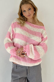 Off-shoulder striped knit sweater in blush pink and white with voluminous sleeves.