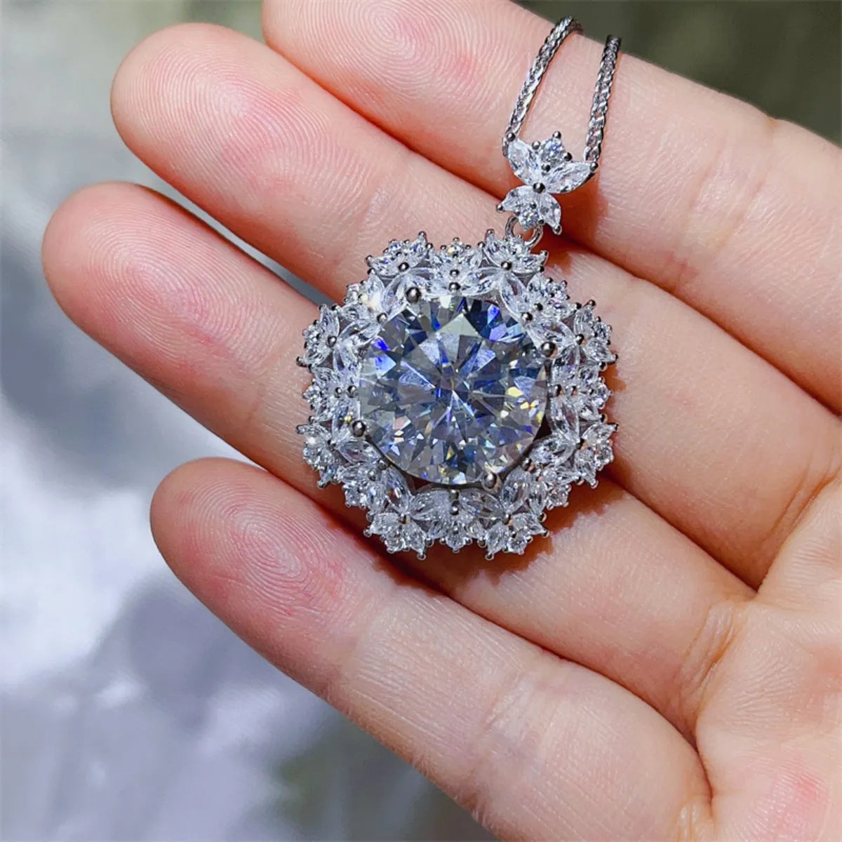 Radiant white cluster pendant necklace with a large central diamond and delicate floral accents.