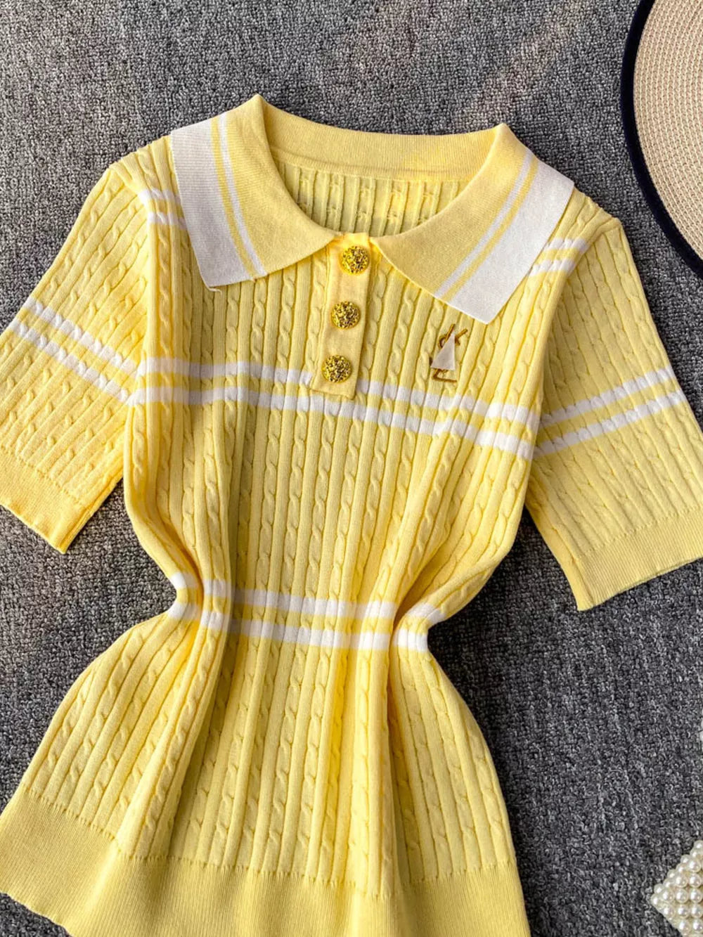 Yellow cable knit polo shirt with white stripes and gold buttons.