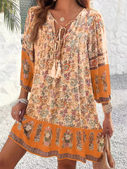 Vibrant floral tassel tie mini dress in ochre with peasant sleeves and tiered hem.