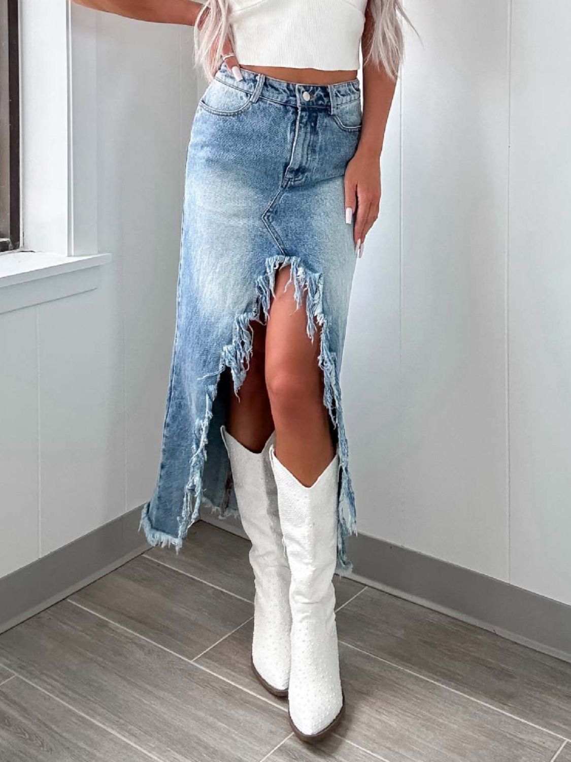 Distressed denim maxi skirt with a high slit and frayed hem in light wash.