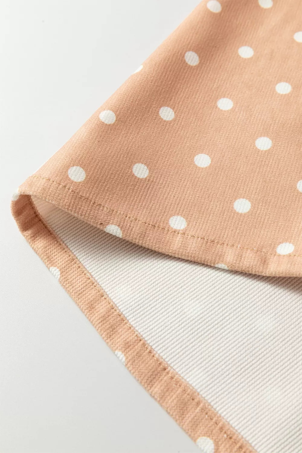 Polka dot maternity trousers in peach with white dots, featuring a wide-leg cut and drawstring detail.