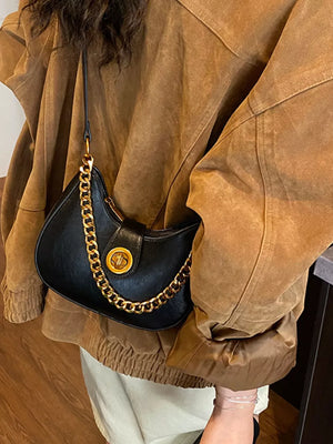 Black crescent mini shoulder bag with gold chain accent and clasp closure.