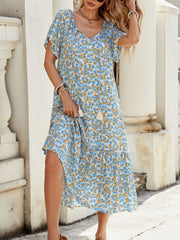 Blue midi dress with daisy print, tie-front neckline, flutter sleeves, and tiered hem.