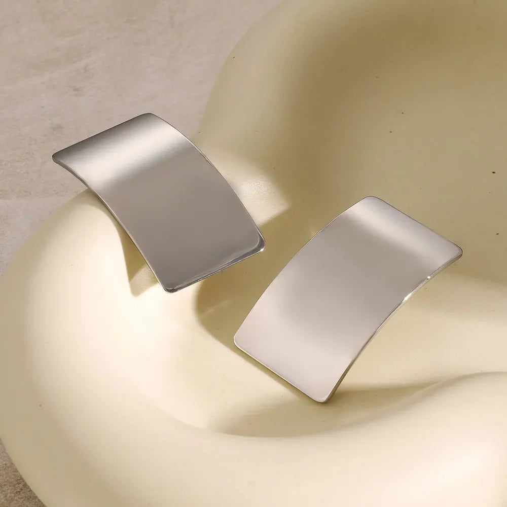 Sculpted silver-tone statement earrings with a bold, curved design.
