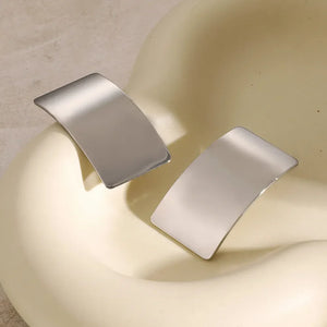 Sculpted silver-tone statement earrings with a bold, curved design.
