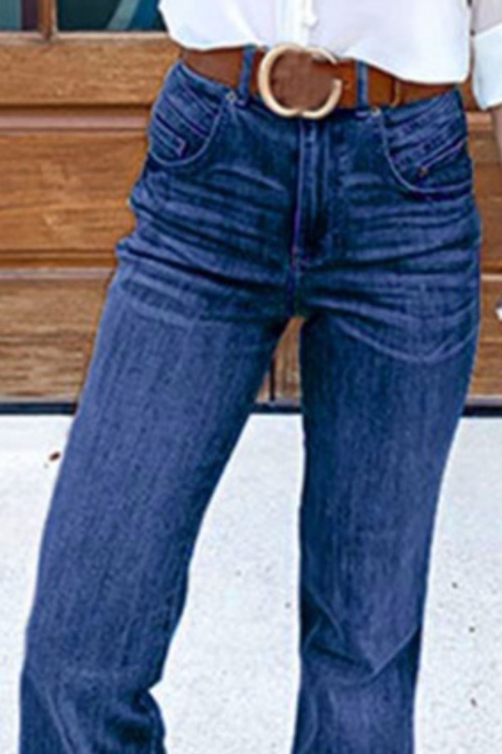 High-waisted denim bell bottom jeans in medium wash with a brown belt.