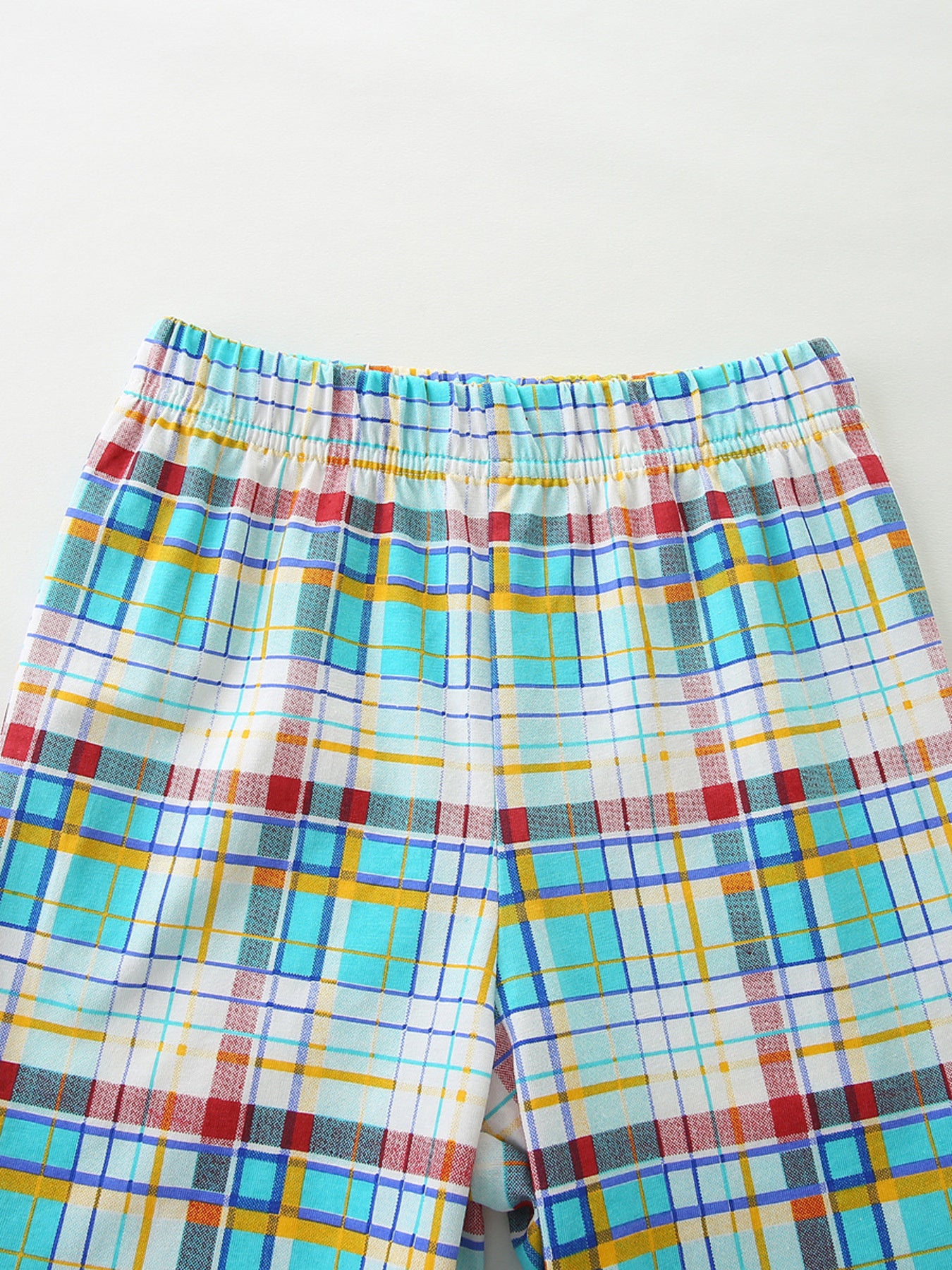 Baby shorts with elastic waistband and colorful plaid pattern in blue, yellow, and red cotton.