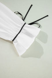 White blouse with black piped trim and tie detail on sleeve cuff