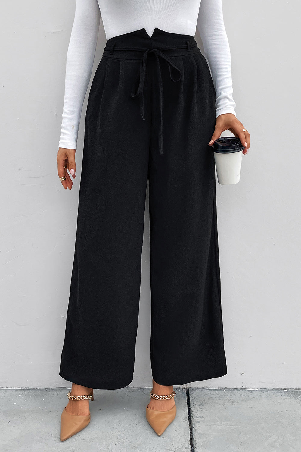 Black high-waist tie palazzo trousers with a wide leg, styled with a white long-sleeve top.