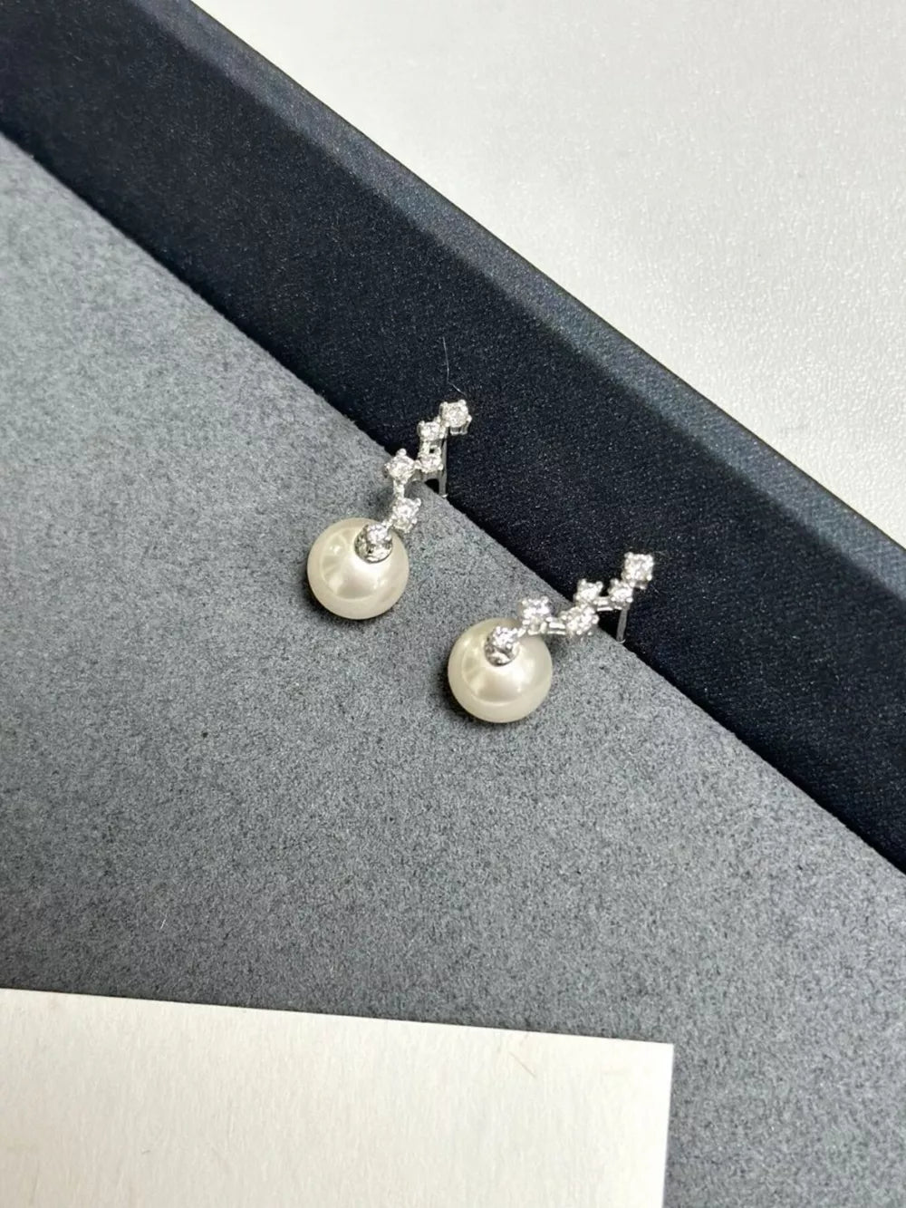 Elegant sterling silver drop earrings with ivory pearls and zircon accents.