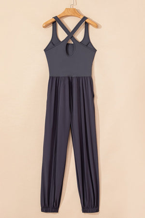 Dark gray jumpsuit with cutout bodice, crisscross straps, gathered waist, and cuffed legs.