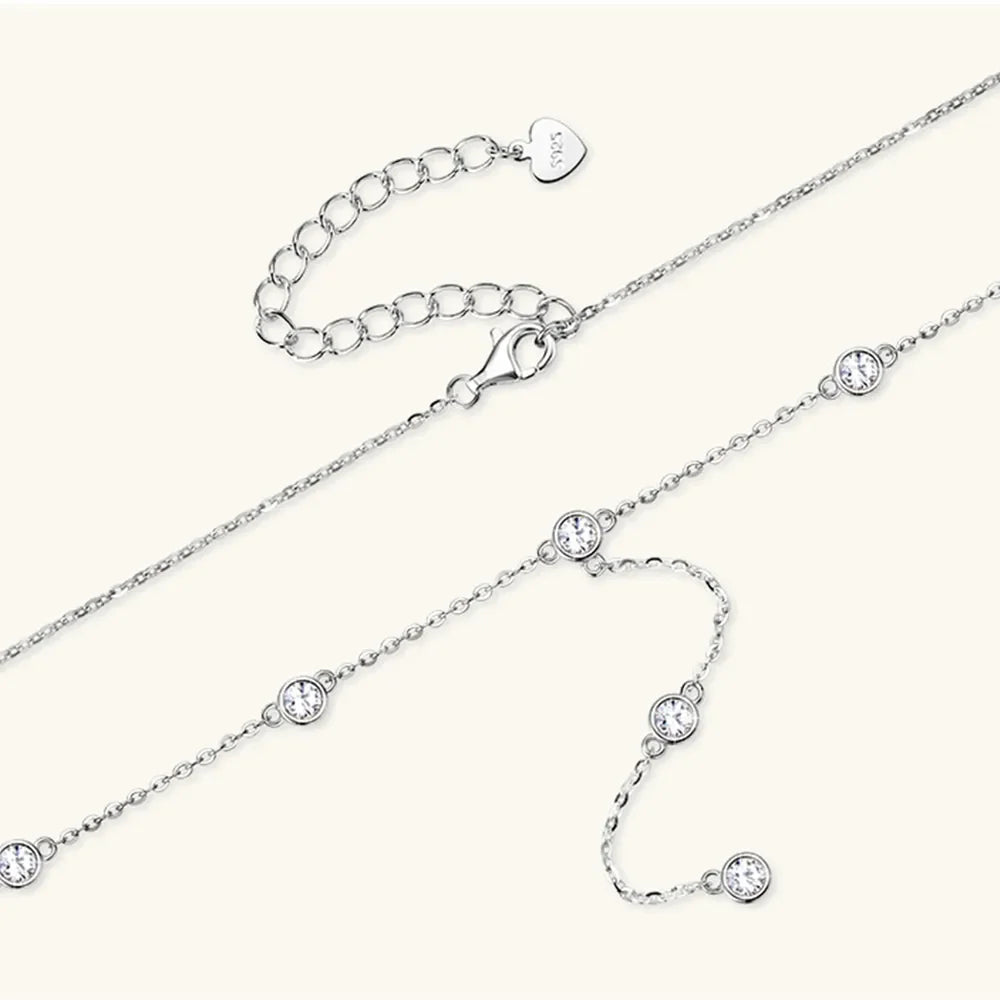 Silver lariat necklace with bezel-set moissanite stones and adjustable clasp.
