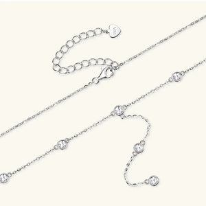 Silver lariat necklace with bezel-set moissanite stones and adjustable clasp.