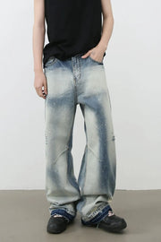 Distressed painterly wide-leg jeans in medium wash denim with paint splatters and artistic paneling.