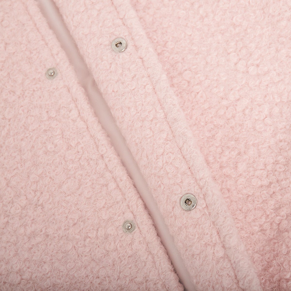 Blush pink textured bouclé bomber jacket with rounded neck and snap closures.
