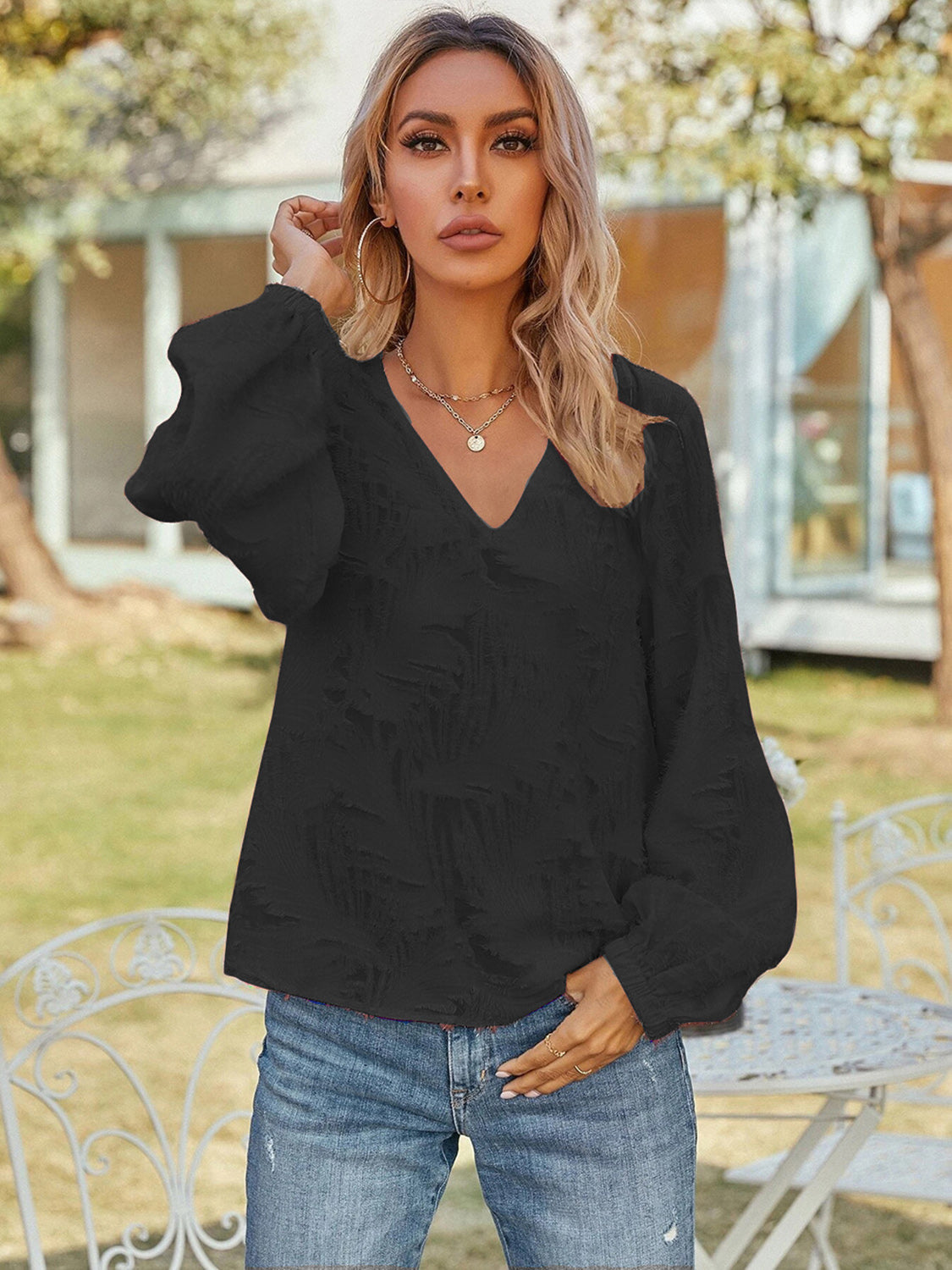 Black textured puff sleeve v-neck blouse with voluminous sleeves.