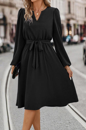 Black midi dress with V-neck, poet sleeves, and tie waist.
