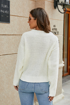 White ribbed knit sweater with a cross-front detail, crew neck, and long sleeves.