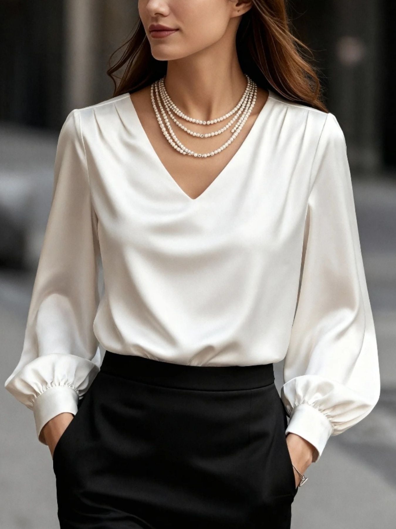 White satin V-neck long sleeve blouse with gathered cuffs, styled with pearls