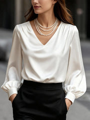White satin V-neck long sleeve blouse with gathered cuffs, styled with pearls