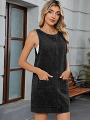 Sleeveless black denim pinafore dress with front pockets and a round neckline.