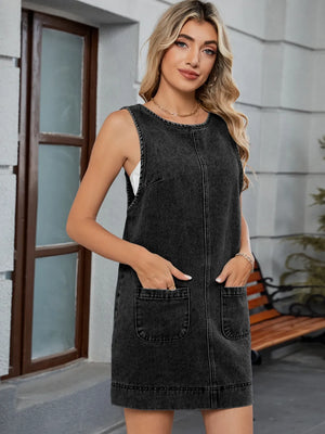 Sleeveless black denim pinafore dress with front pockets and a round neckline.