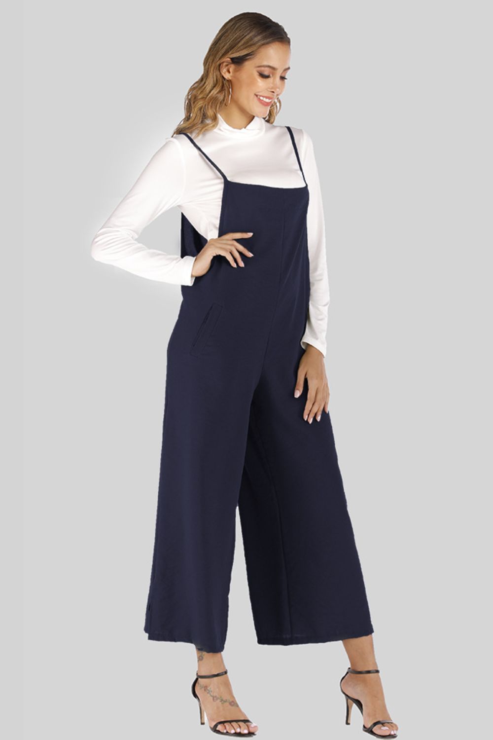 Dark Navy culotte overalls with slender straps and wide legs, worn over a white turtleneck.