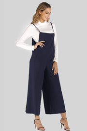 Dark Navy culotte overalls with slender straps and wide legs, worn over a white turtleneck.