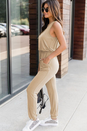 Tan sleeveless jumpsuit with drawstring waist and pockets, cuffed ankles