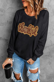 Black crewneck sweatshirt with sequin "thankful" graphic.
