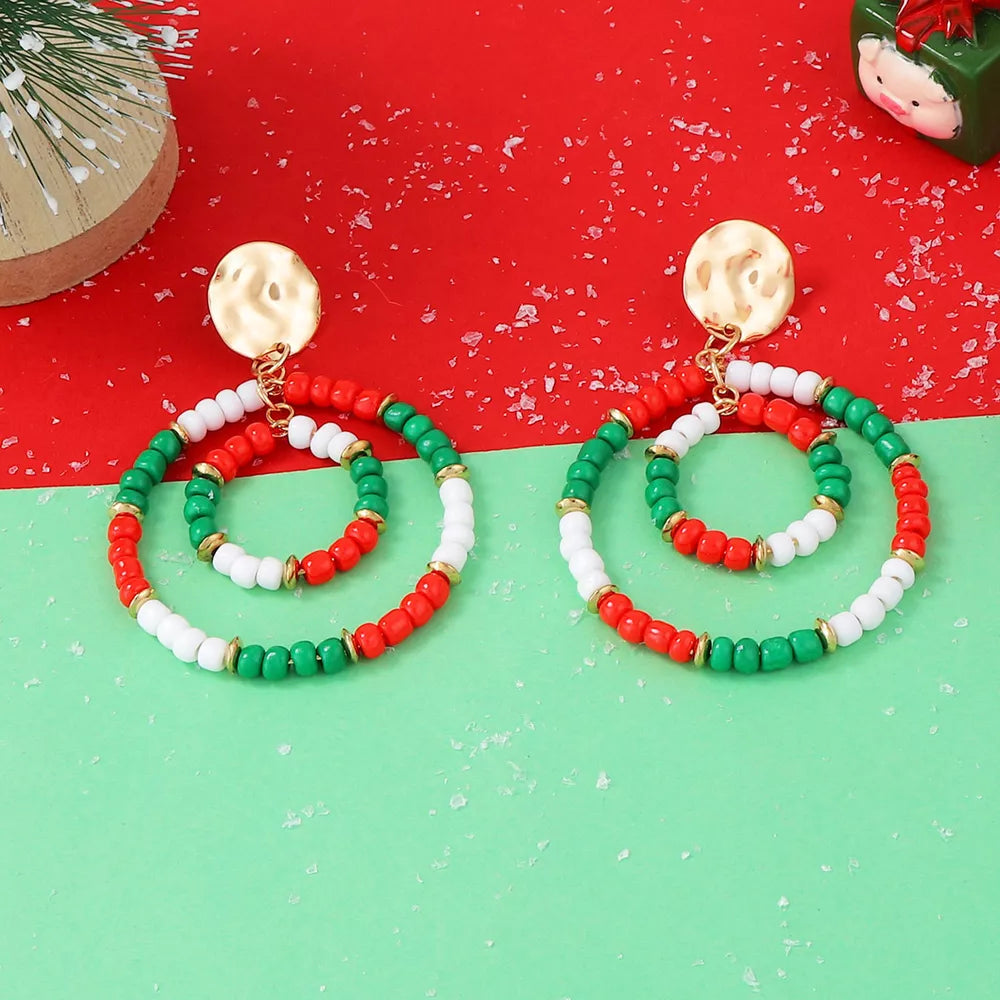 Festive beaded hoop earrings in red, white, and green with gold accents.