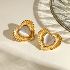 Golden heart cabochon stud earrings with ribbed gold frames and iridescent white centers.