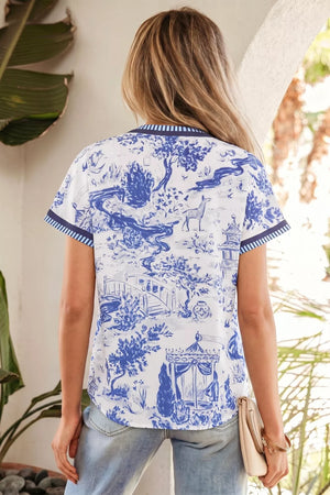 Blue and white toile print V-neck blouse with striped accents and short sleeves.