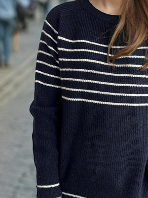 Dark blue ribbed knit crewneck sweater with white Breton stripes and long sleeves.