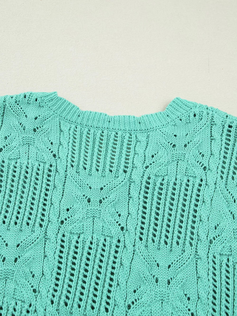 Teal pointelle knit sweater with scalloped trim and openwork pattern.