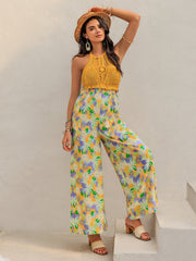Gold crochet halter jumpsuit with a vibrant floral print palazzo pant and wide leg.